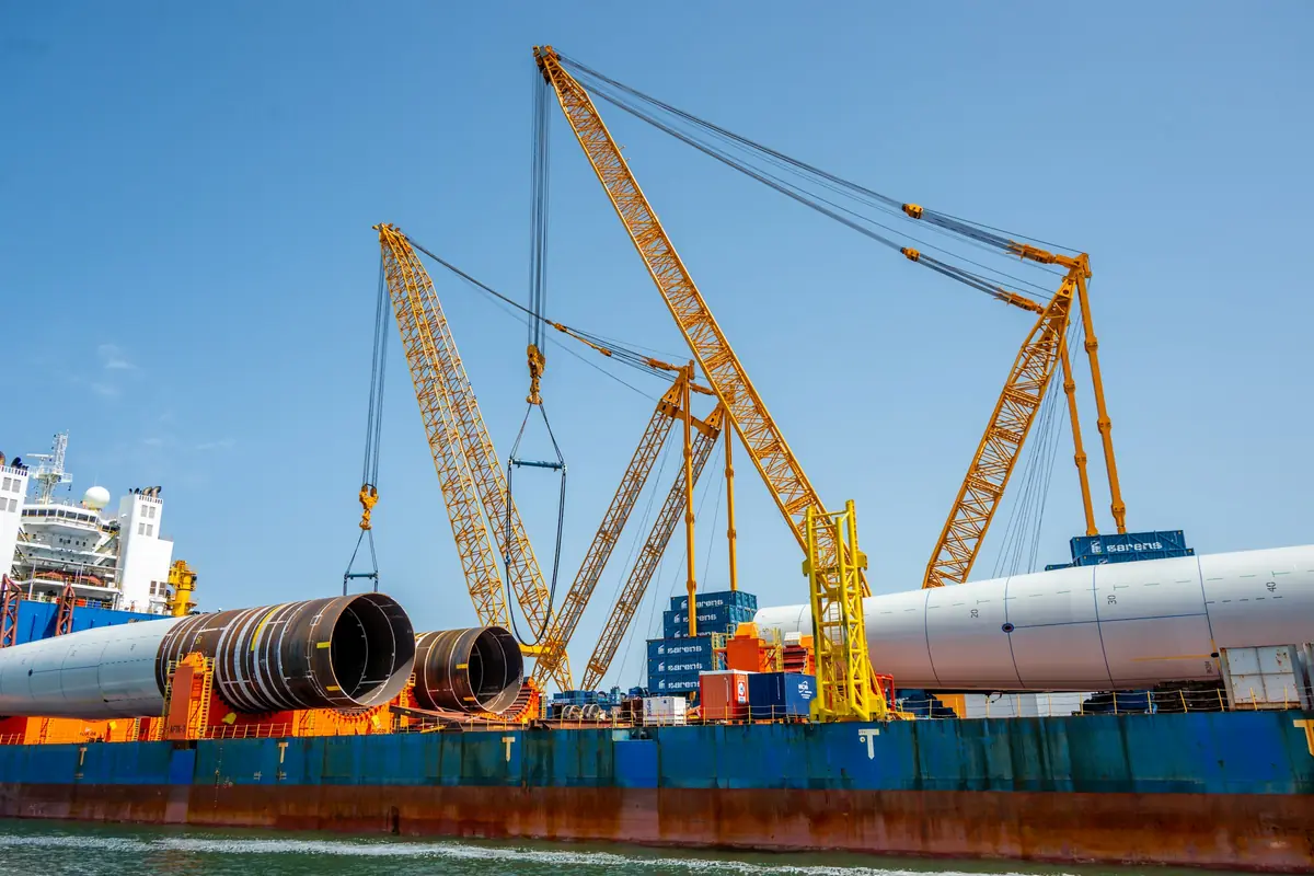 Heavy-lift cranes loading large cylindrical cargo onto a vessel